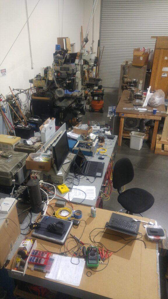 The lab bench: oscilloscope showing a pressure waveform, signal generator, and the glass calibration chamber