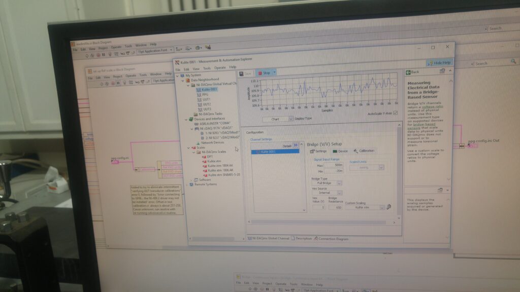 Monitor showing LabVIEW block diagrams and the bridge-sensor channel configuration with a live signal chart