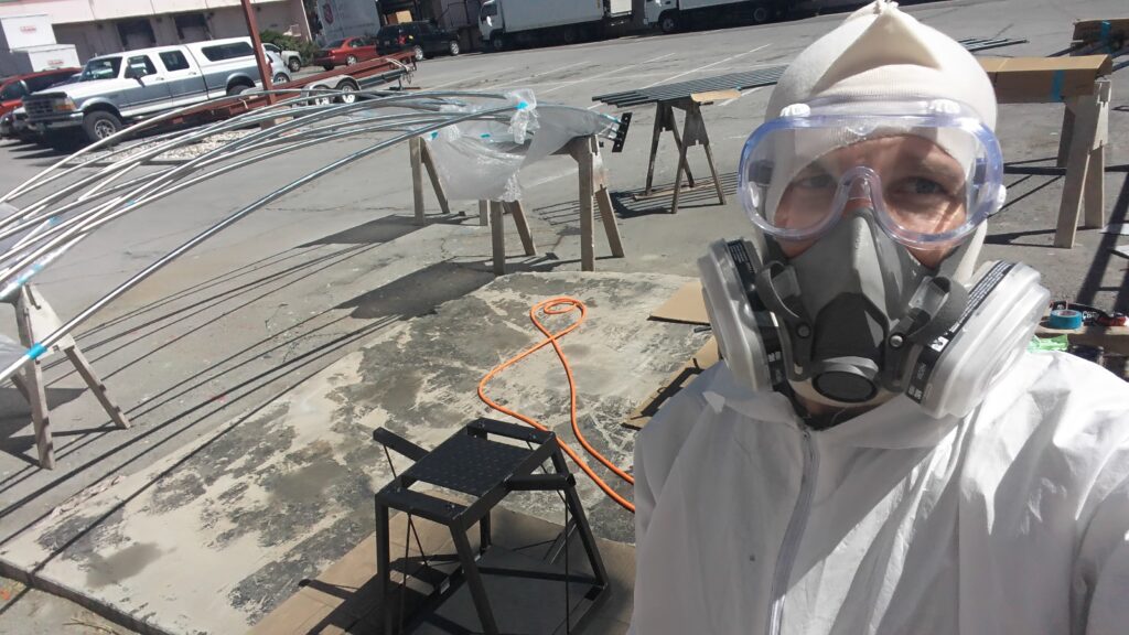 In a Tyvek suit, respirator, and goggles, recoating the arcs outside The Generator
