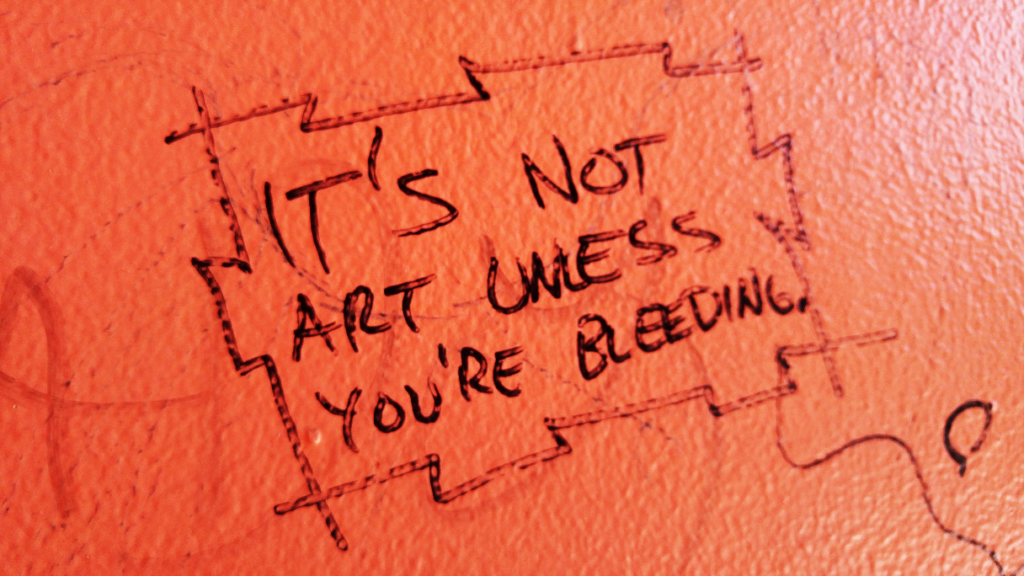 Hand-drawn graffiti on an orange wall: it’s not art unless you’re bleeding