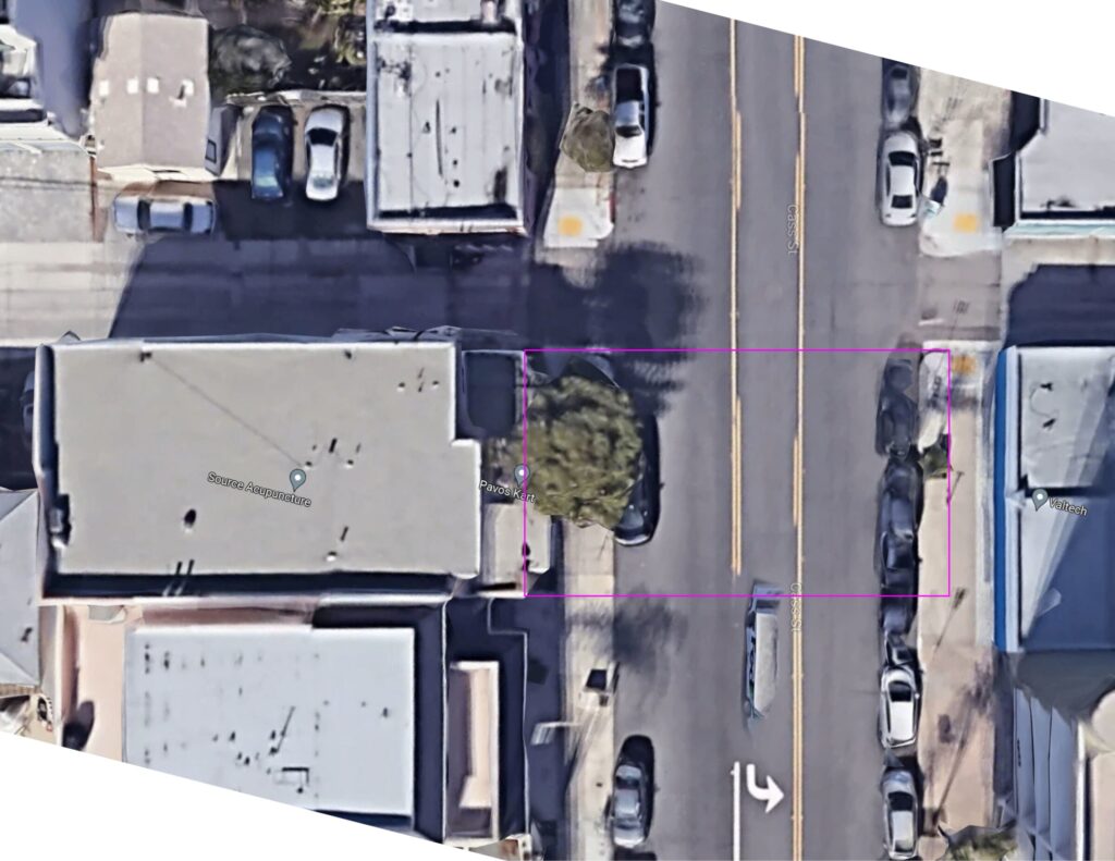 An overhead satellite view of the building and the street in front of it, with a magenta rectangle drawn from the building face across to the far sidewalk.