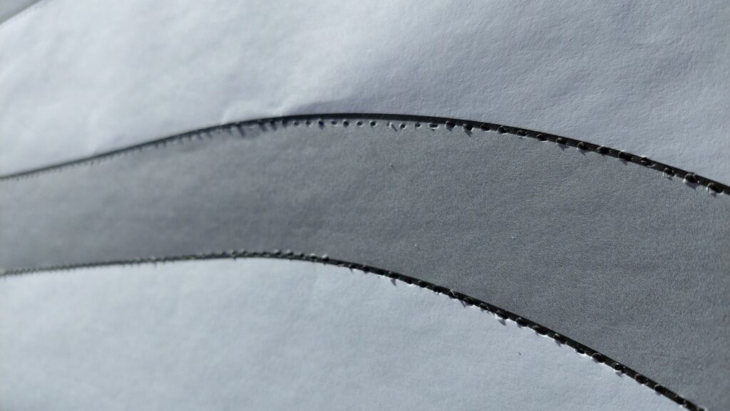 A close view of the printed pattern showing a curved line perforated with a dense row of small punched holes