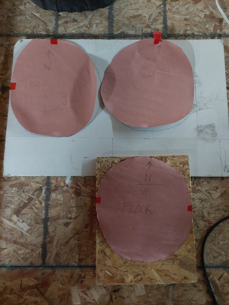 Paper and hardboard templates with registration marks laid over the floor, used to cut exact patches for the old openings