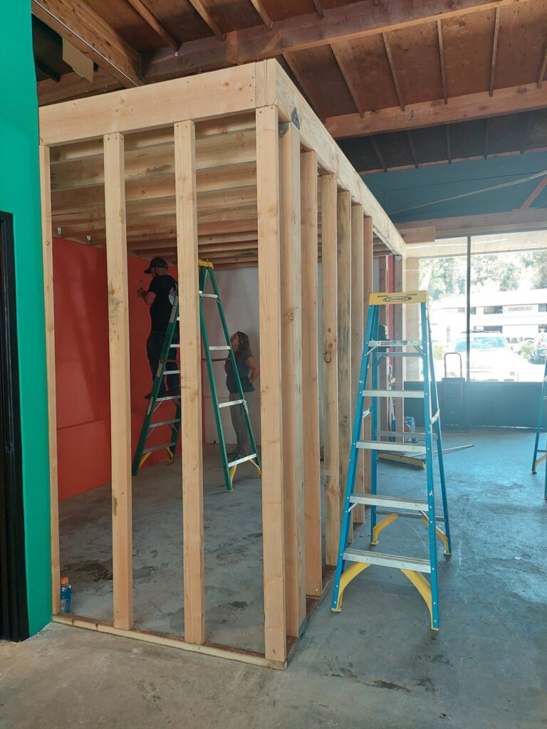 New stud framing for the laser room going up inside the open shop, a stepladder alongside