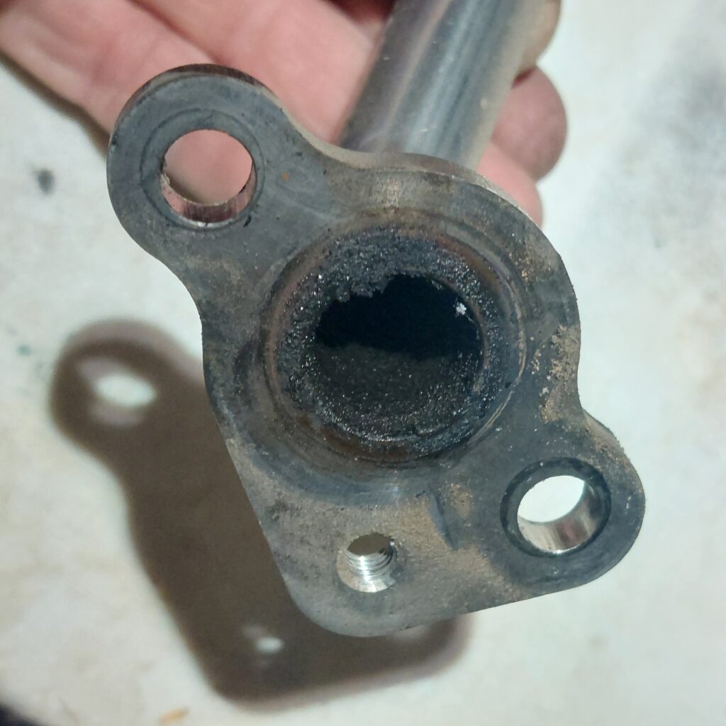 The bore of the EGR tube seen end-on, its opening reduced to a narrow slot by a thick uniform layer of hard black carbon