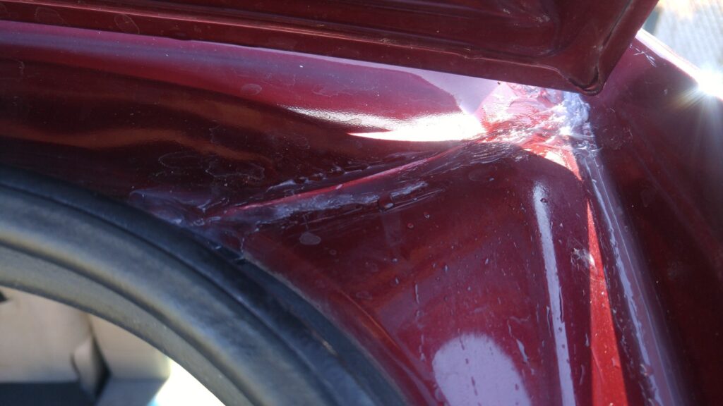 Fresh sealant worked into the upper corner of the rear hatch opening, along the seam where the roof panel meets the body