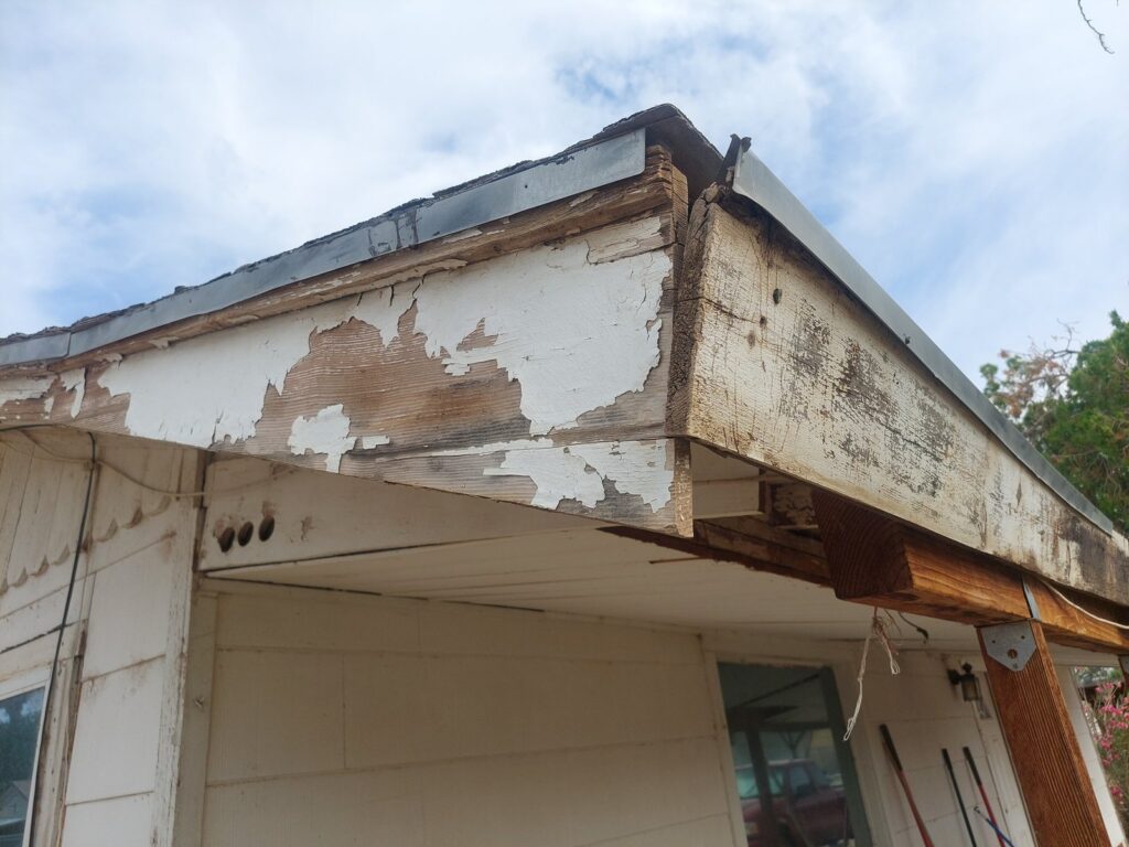 A roof corner with the fascia and rake boards rotted away, exposing the framing beneath