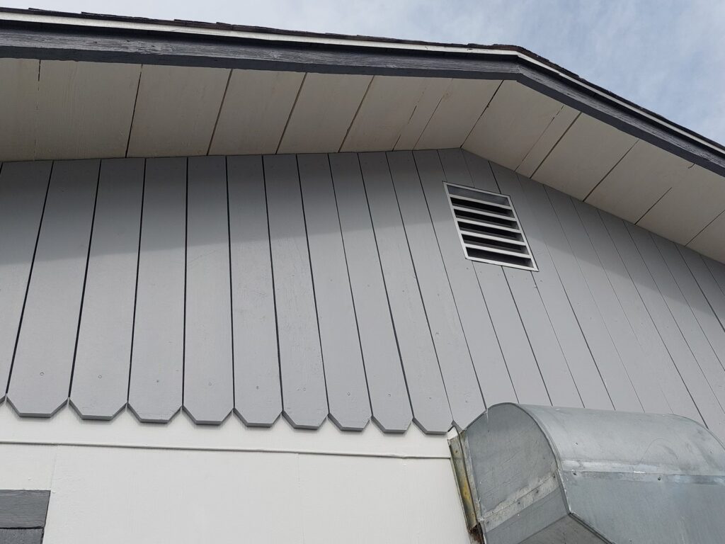 The same gable, new boards fitted and painted, with the louvred vent reset