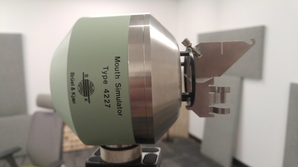 A Brüel & Kjær Type 4227 mouth simulator on a stand in the part-finished treated room, grey absorber panels behind it